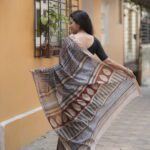 Woman draping a striped Maroon and Blue Maheshwari Bagh print saree showing the elegant fall and pallu.