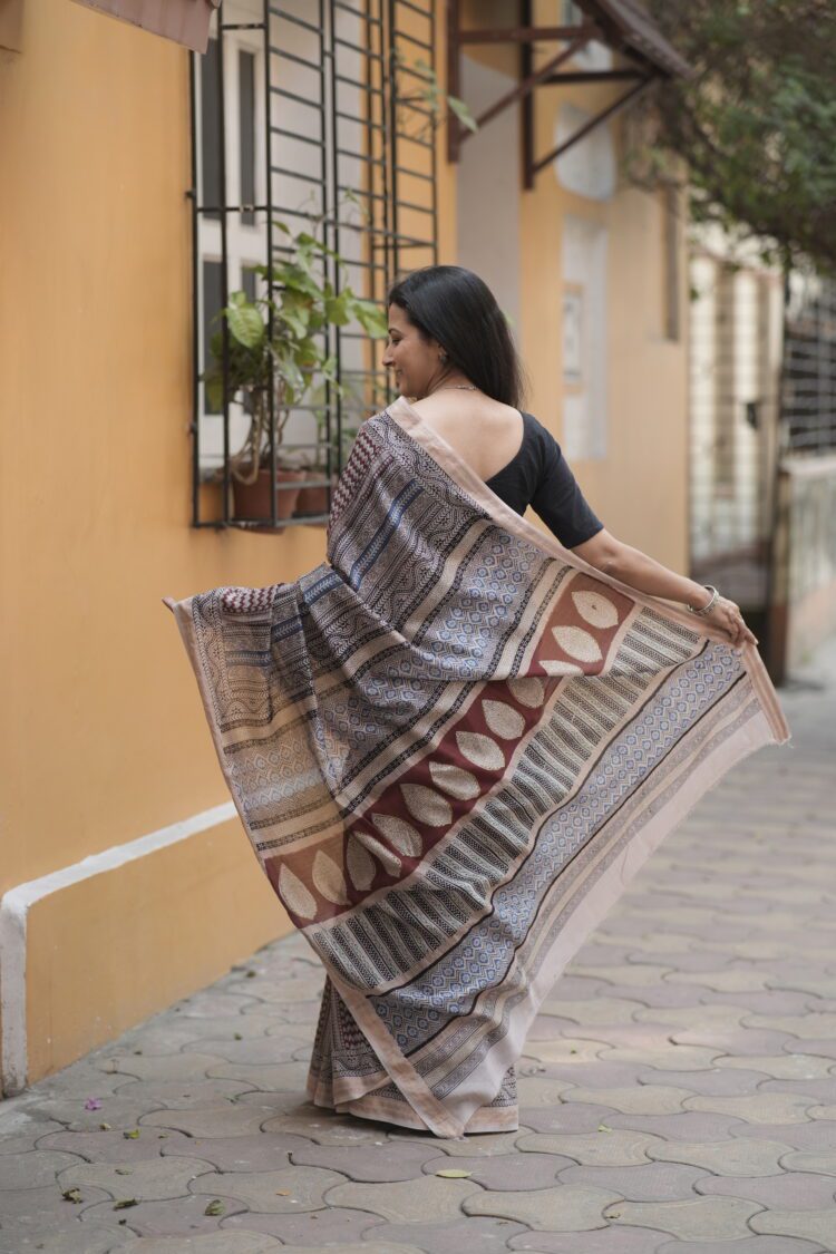 Woman draping a striped Maroon and Blue Maheshwari Bagh print saree showing the elegant fall and pallu.
