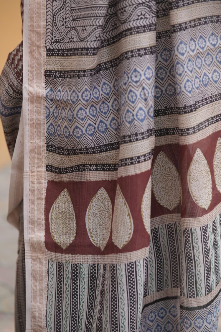 Close-up of the intricate Bagh hand-block print motifs on a maroon and black Maheshwari fabric.