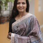 Woman draping a striped Maroon and Blue Maheshwari Bagh print saree showing the elegant fall and pallu.