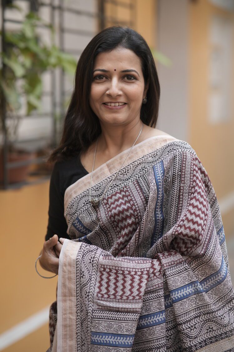 Woman draping a striped Maroon and Blue Maheshwari Bagh print saree showing the elegant fall and pallu.