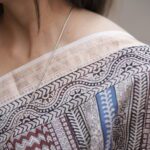 Woman draping a striped Maroon and Blue Maheshwari Bagh print saree showing the elegant fall and pallu.