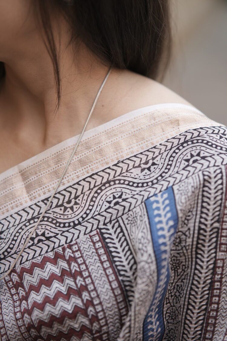 Woman draping a striped Maroon and Blue Maheshwari Bagh print saree showing the elegant fall and pallu.