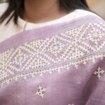 Mauve Tussar silk saree featuring intricate beige Gujarati hand embroidery throughout the body and border.