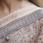 Detailed view of the intricate Maroon and Yellow Jal motifs on the sheer texture of a Beige Maheshwari handloom saree.