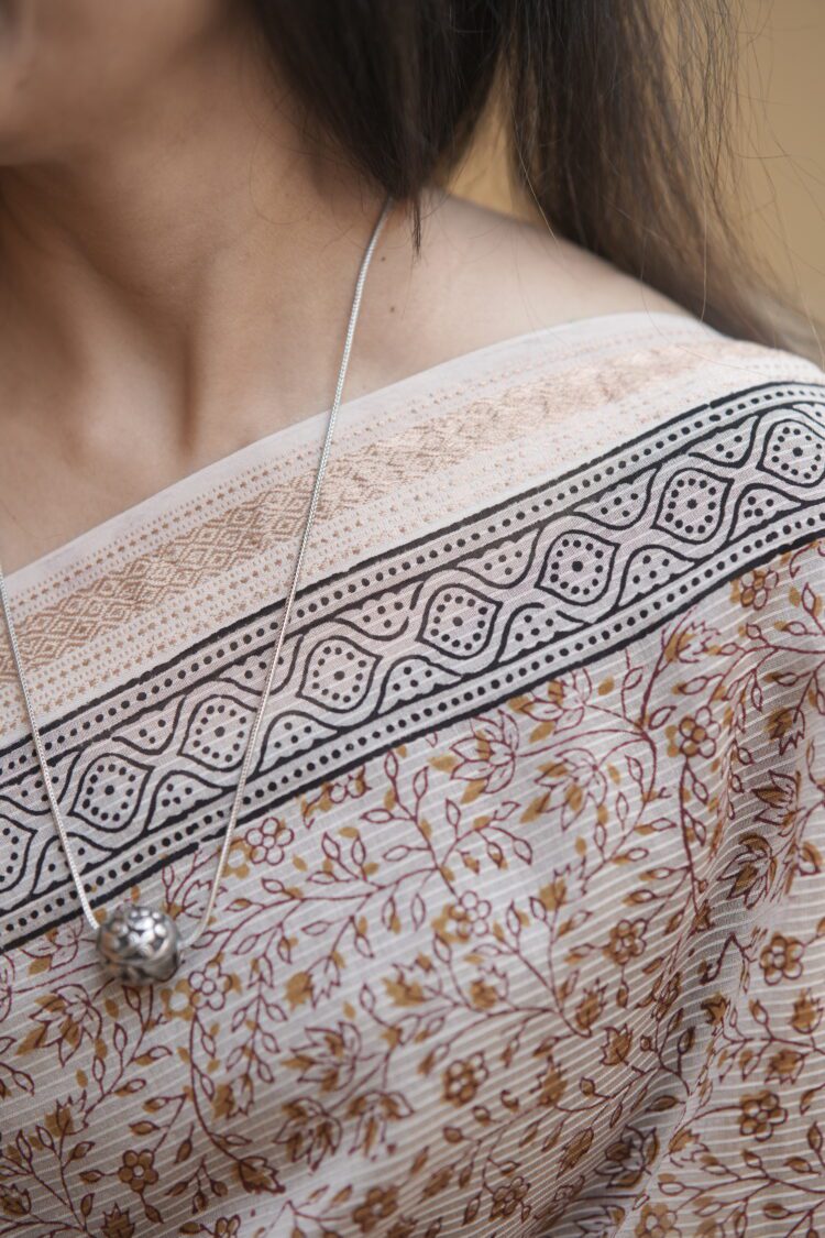 Detailed view of the intricate Maroon and Yellow Jal motifs on the sheer texture of a Beige Maheshwari handloom saree.