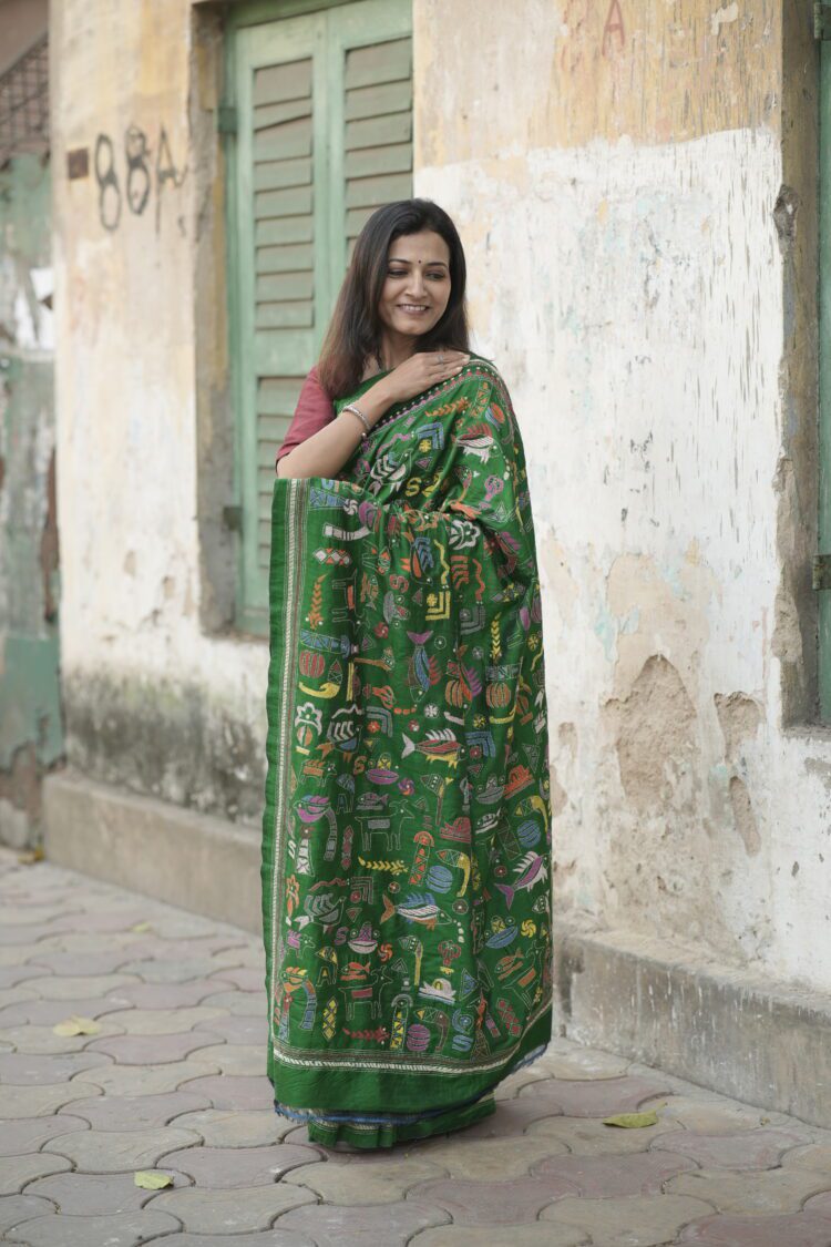 Green silk saree featuring heavy Kantha hand embroidery diagonally from pallu to pleats with rich handcrafted detailing.