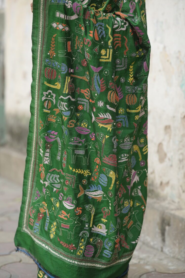 Close-up of Kantha hand embroidery on green silk saree showing dense diagonal stitch work from pallu area.