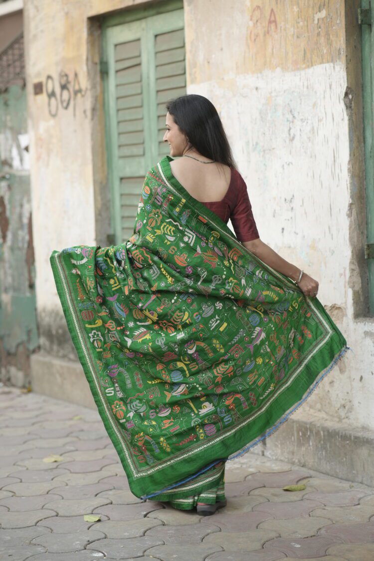 Close-up of Kantha hand embroidery on green silk saree showing dense diagonal stitch work from pallu area.