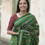 Close-up of Kantha hand embroidery on green silk saree showing dense diagonal stitch work from pallu area.
