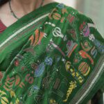 Green silk saree featuring heavy Kantha hand embroidery diagonally from pallu to pleats with rich handcrafted detailing.